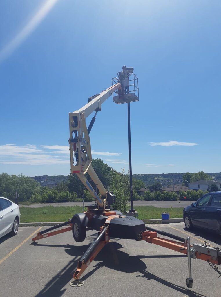 Installation d'un lampadaire extérieur avec l'aide d'une nacelle élévatrice.